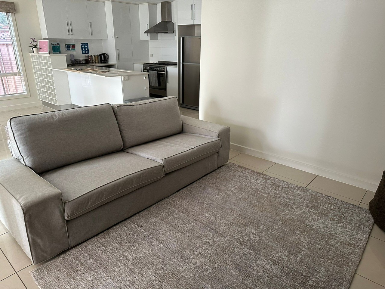 Comfortable grey fabric sofa on a large floor rug in an open-plan living room.