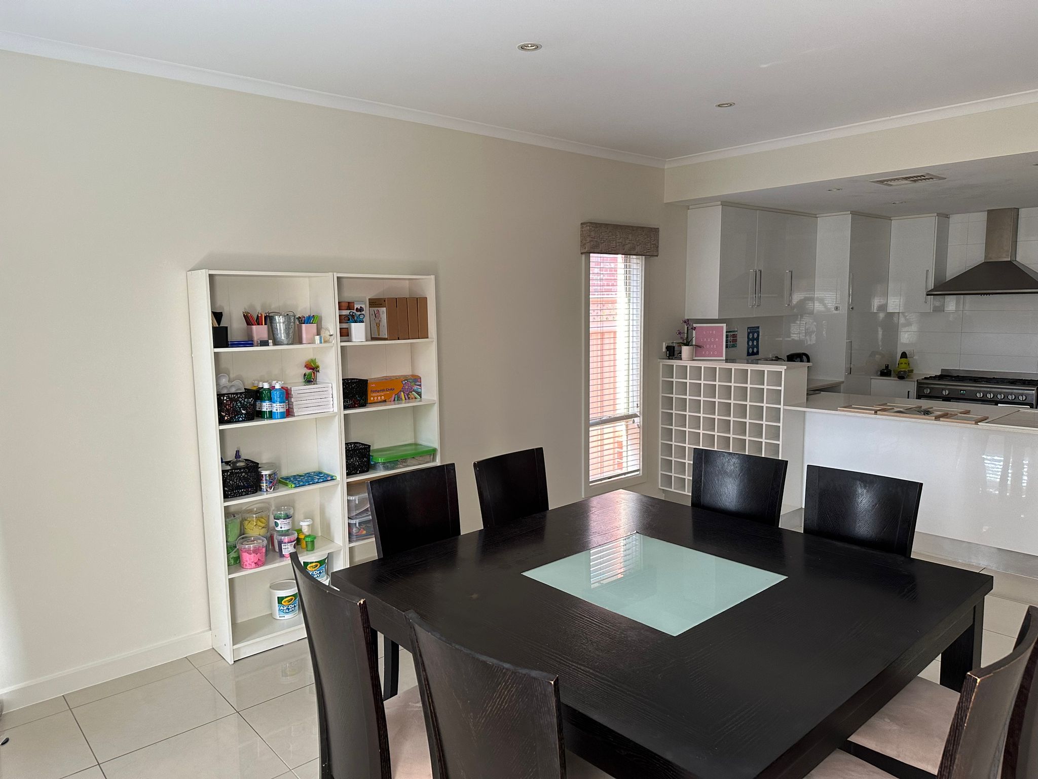 Spacious dining table with black chairs adjacent to an open-plan modern white kitchen.