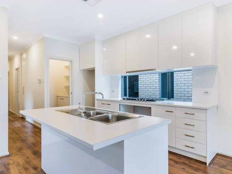 Central kitchen island bench with a double stainless steel sink and white stone countertops.
