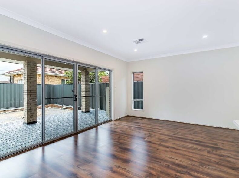 Sunlit living area with polished timber flooring and large sliding glass doors leading to the outdoor patio.