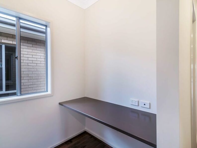 Built-in study desk counter with wall power outlets next to a window in a quiet corner.